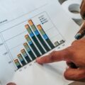 Close-up of hands pointing at a financial market activity chart, analyzing trends in securitization.
